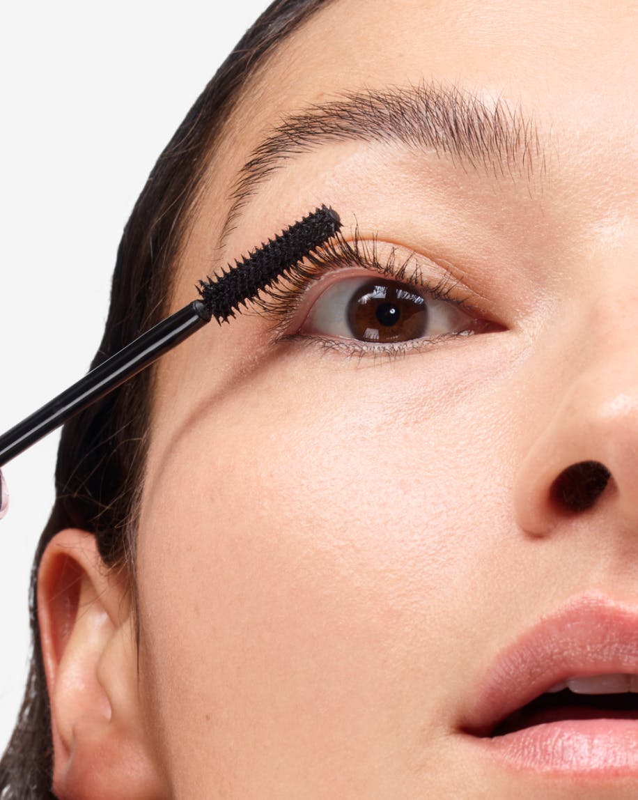 close up of model applying lash slick black to eyelashes